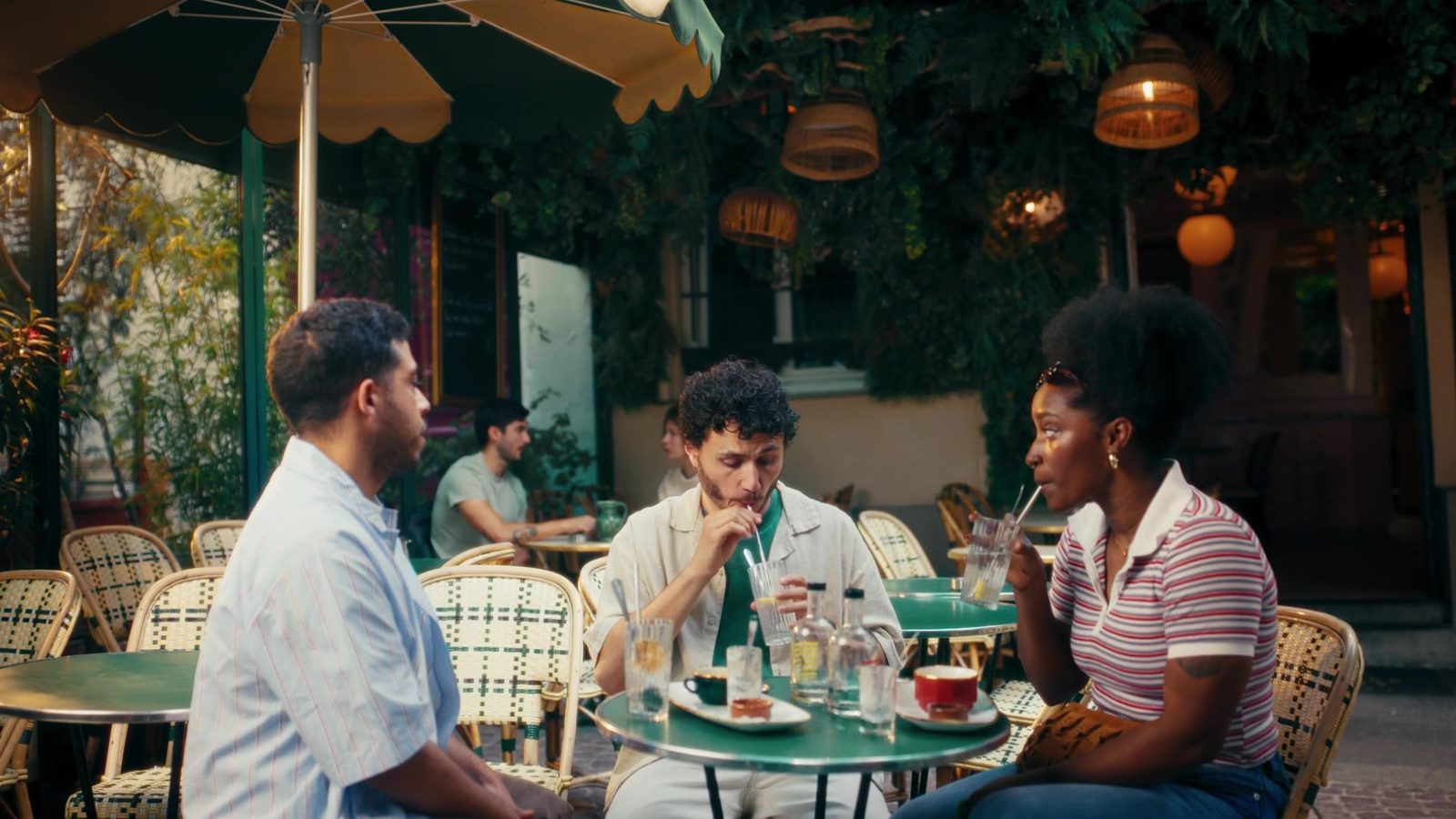 Trois amis attablés à une terrasse de café.